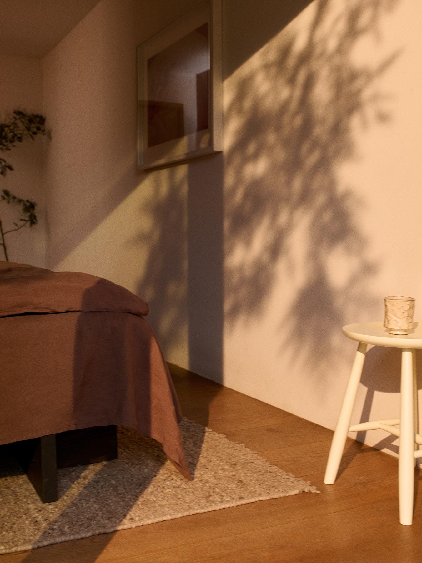 beige ullmatta och pall vid fotändan på en säng